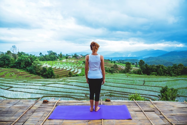 Asian woman relax in the holiday. Play if yoga. On the balcony landscape Natural Field