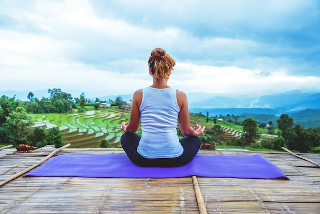 Asian woman relax in the holiday. Play if yoga. On the balcony landscape Natural Field