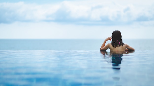 Asian woman relax in pool on beach