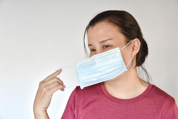 Asian woman removing a mask from her face