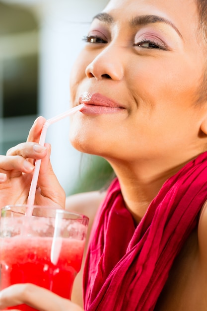 アジアの女性のレストランで飲む