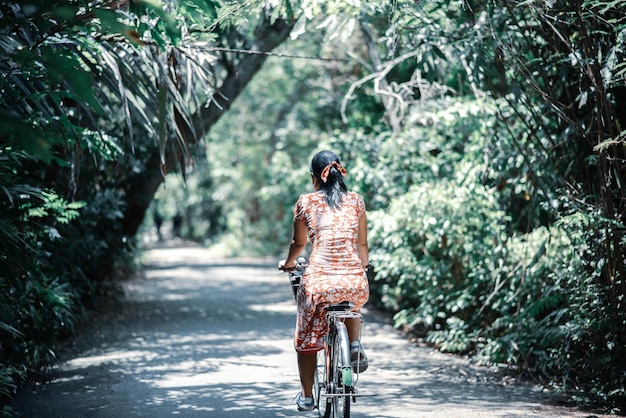 Photo asian woman riding bicycle in the city park