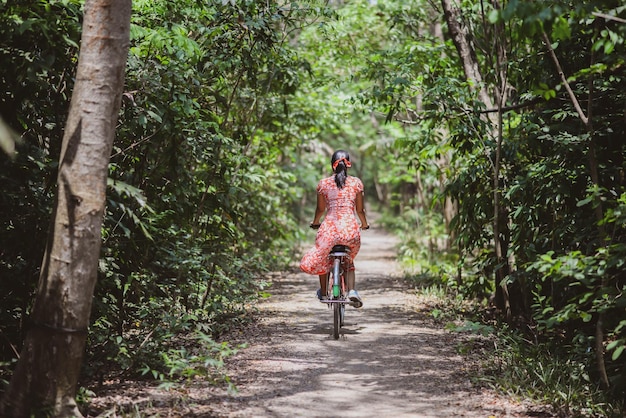 Foto donna asiatica in bicicletta nel parco cittadino