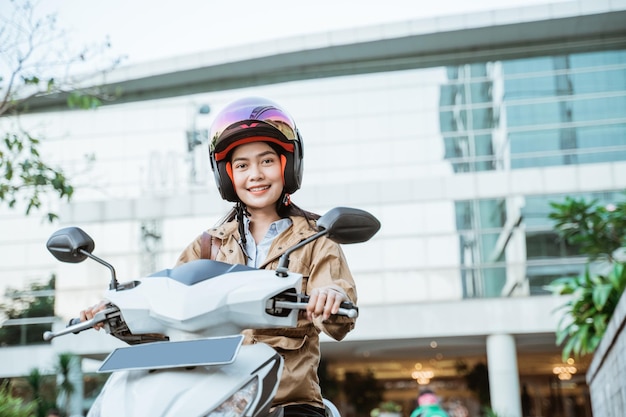 Asian woman riding a motorcycle wearing a helmet on the street