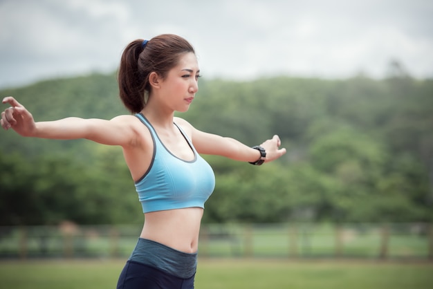 スタジアムでウォームアップと運動をするアジアの女子ランナー