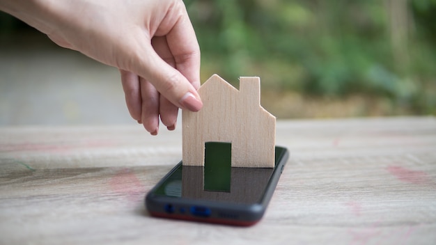 Mano della donna asiatica che tiene la casa in legno, utilizzare per l'acquisto di un nuovo concetto di casa.