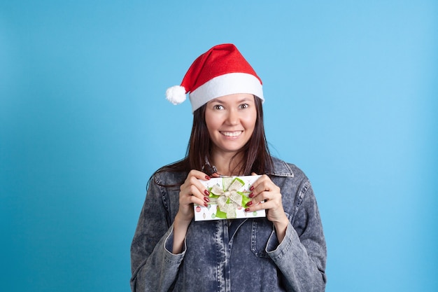 Photo asian  woman in a santa hat holding a green gift box