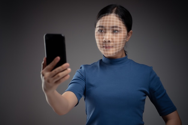 La donna asiatica esegue la scansione del viso tramite smart phone utilizzando il sistema di riconoscimento facciale