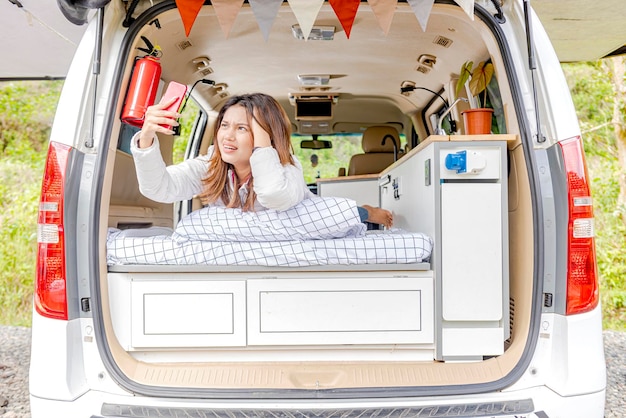 Asian woman searching the signal for her mobile phone inside the campervan