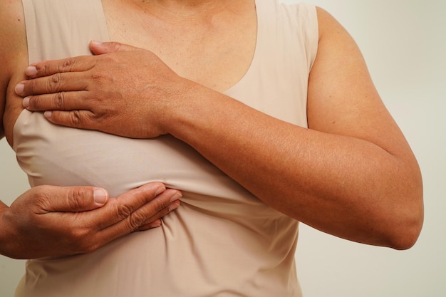 Азиатская женщина прикасается к себе контрольной опухолью или раком молочной железы Самостоятельный осмотр груди