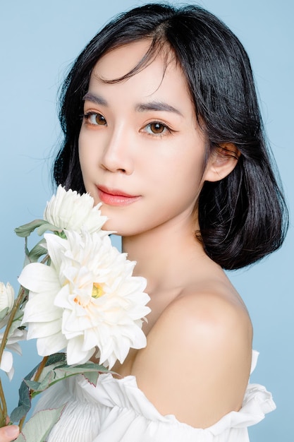 Asian woman short hair with Perfect clean fresh skin Cute female model with natural makeup and sparkling eyes on blue isolated background Facial treatment Cosmetology beauty Concept