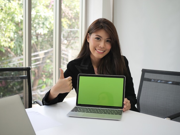 Photo asian woman showing thumb up and holding laptop in hands.