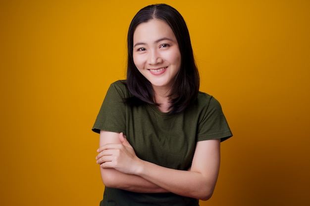 Asian woman showing toothy smile standing isolated over yellow wall.