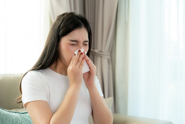 アジアの女性の鼻にくしゃみとティッシュペーパーに冷たい咳で病気と悲しい