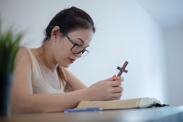 아시아 여성이 앉아서 성경을 공부하는 동안 메모를 한다