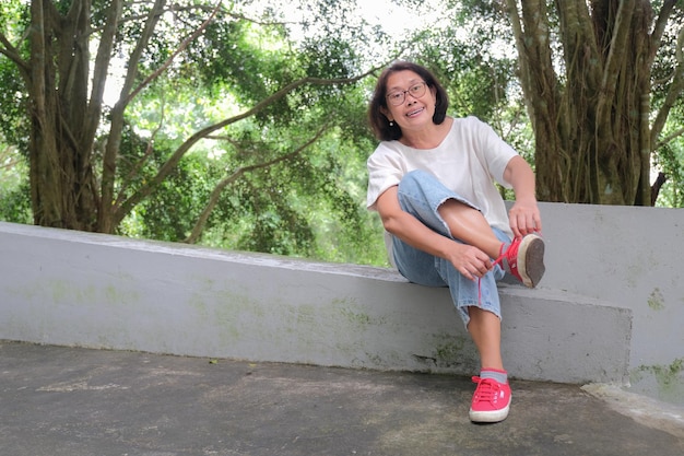 Asian woman sitting alone in the park fixing her shoe lace after a long walk