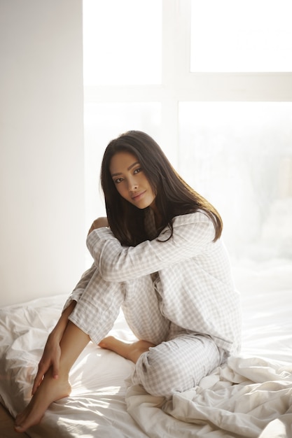 Asian Woman Sitting on Bed at Home