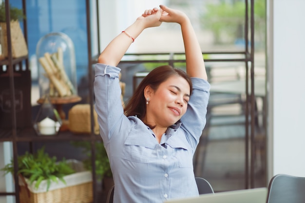 Donna asiatica che si siede nel caffè e nell'allungamento