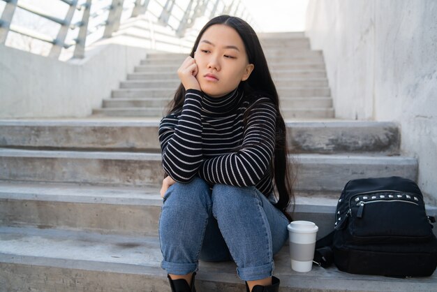 Asian woman sitting on concrete stairs.