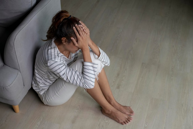 Foto donna asiatica seduta a terra a casa sentendosi triste stanca e preoccupata soffre di depressione nella salute mentalefemale soffre di problemi di salute mentale