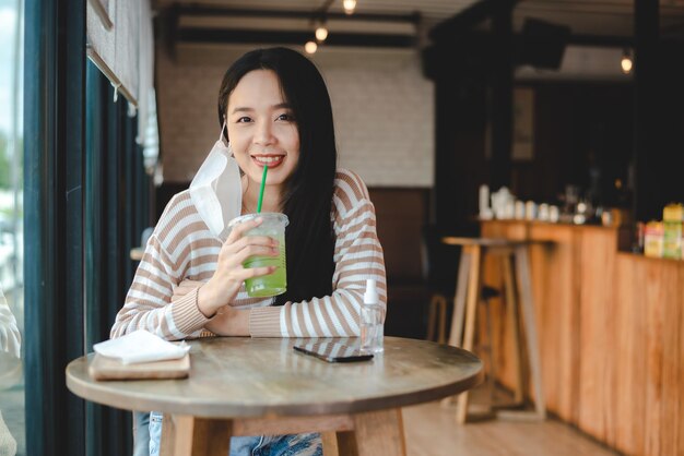 Asian woman sitting separated in restaurant eating food keep social distance to prevent covid19