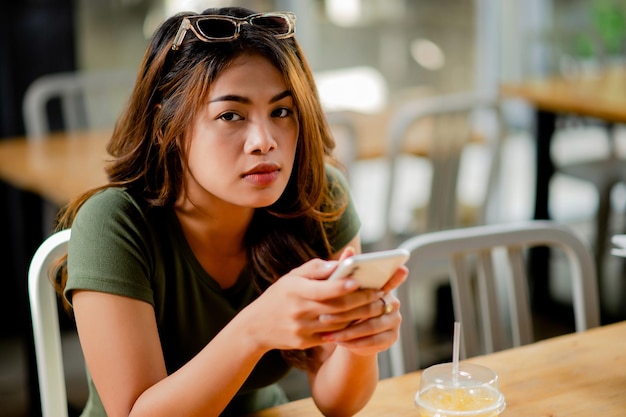 Азиатская женщина сидит и работает со смартфоном Общаться онлайн Работа онлайн и играть в социальные игры