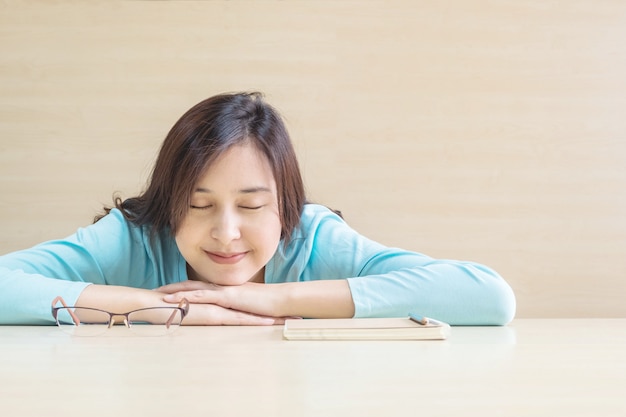 Asian woman sleep by lied on desk with happy face in rest time from reading book 