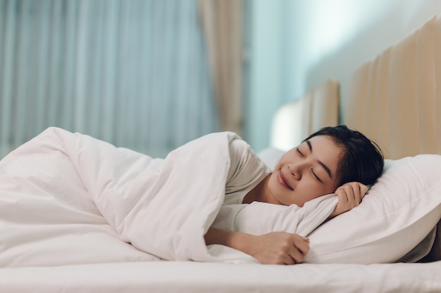 Asian woman sleeping in a bed in a dark bedroom