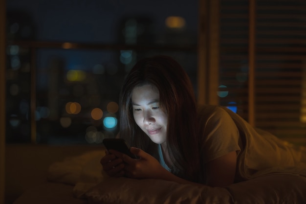 Asian woman sleeping and using smart mobile phone for social network or video conference