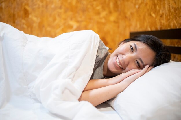 An Asian woman sleeping on a white mattress