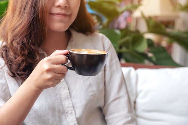 カフェで気持ちよくホットコーヒーの香りと飲み物を飲むアジアの女性