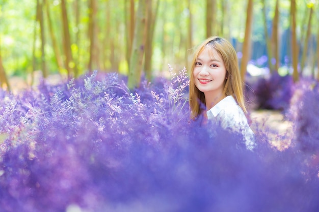 아시아 여성은 자연 테마의 전경으로 보라색 꽃 정원에서 행복하게 웃는다.