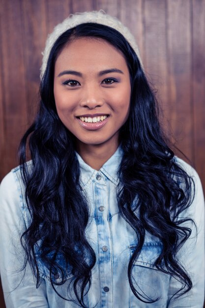 Photo asian woman smiling to the camera against wooden wall