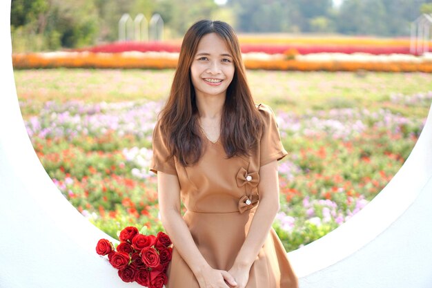 Asian woman smiling happily among beautiful flowers