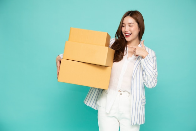 Asian woman smiling and holding package parcel box isolated on light green background.