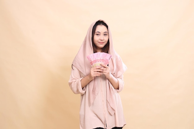 Asian woman smiling with both hands carrying rupiah money young beautiful for finance advertising fa