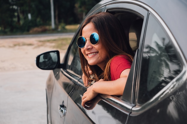 Asian woman smilng with the mirror in the car.