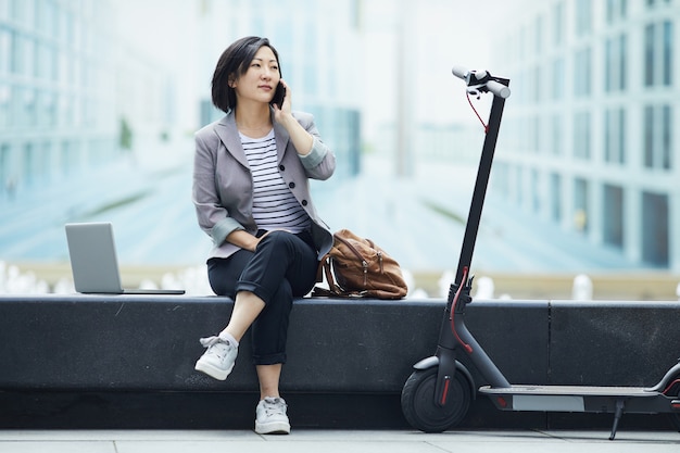 Asian Woman Speaking by Phone in City