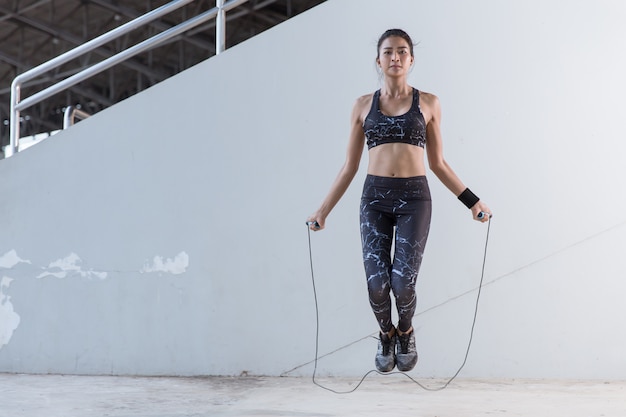 Photo asian woman sports girl doing exercises with jumping rope.