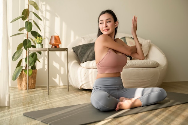 Asian woman in sportswear exercising and doing yoga in living room at home