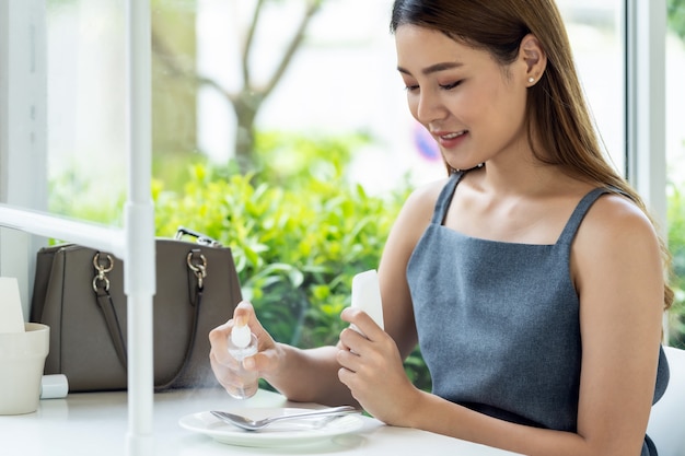 Asian woman spraying alocohol on restauranr dishware