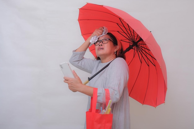 Asian woman standing alone under red umbrella waiting for taxi