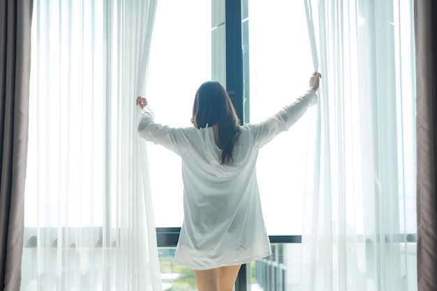 Asian woman standing by the window And stretching in the morning