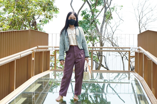 Asian woman standing on a glassfloored observation deck