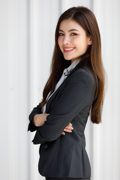 Asian woman standing half length in black suit. Businesswoman holding in business formal suit standing in office room.
Concept Beautiful and confident working woman.