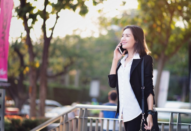 Фото Азиатская женщина, стоя в открытый. счастливая женщина разговаривает по телефону.