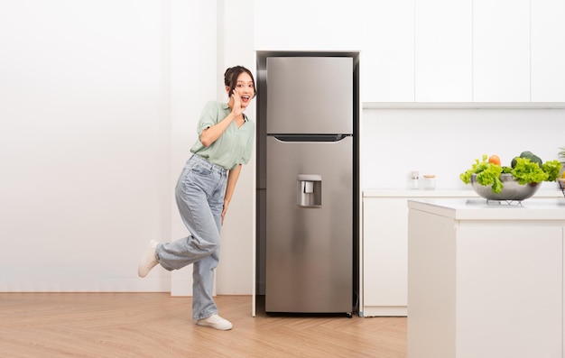 Asian woman standing next to the refrigerator in the kitchen