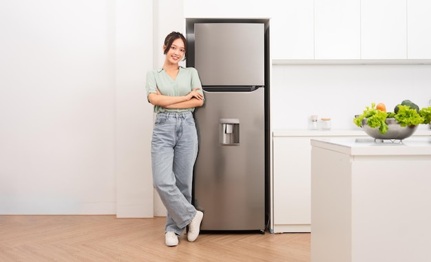 Asian woman standing next to the refrigerator in the kitchen