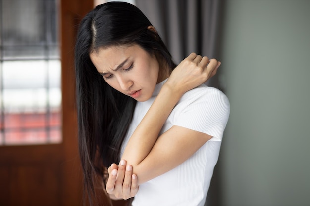 Asian woman suffering from tennis elbow syndrome pain from elbow injury