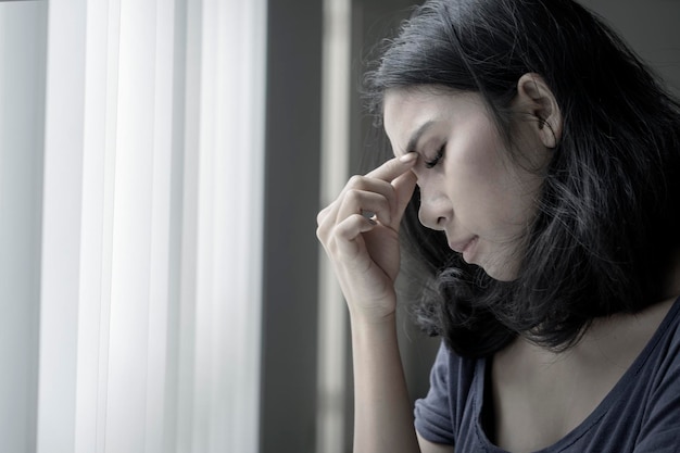 Photo asian woman suffering headache near the window